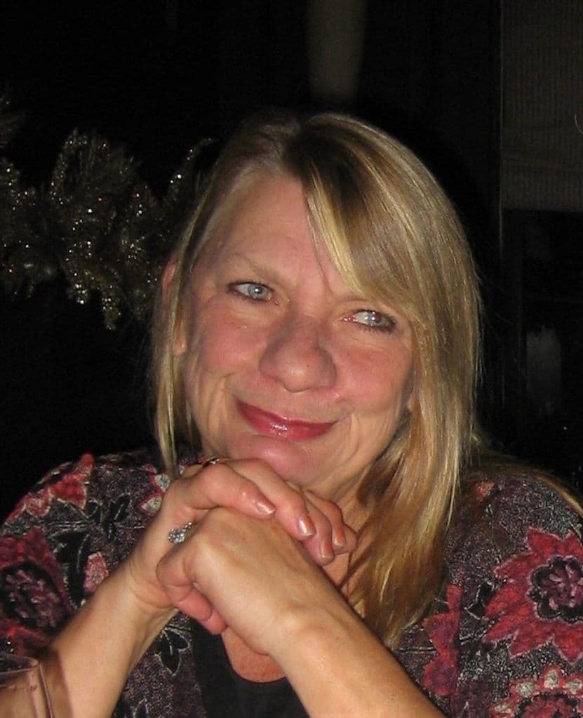 Karole smiling warmly, hands folded under her chin